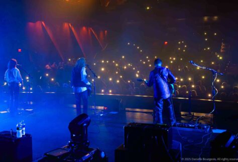 Clint Springer, Jay Bourgeois, and Harry Ochsenbein of Already Gone gaze out from the stage at a sea of glowing cell phones