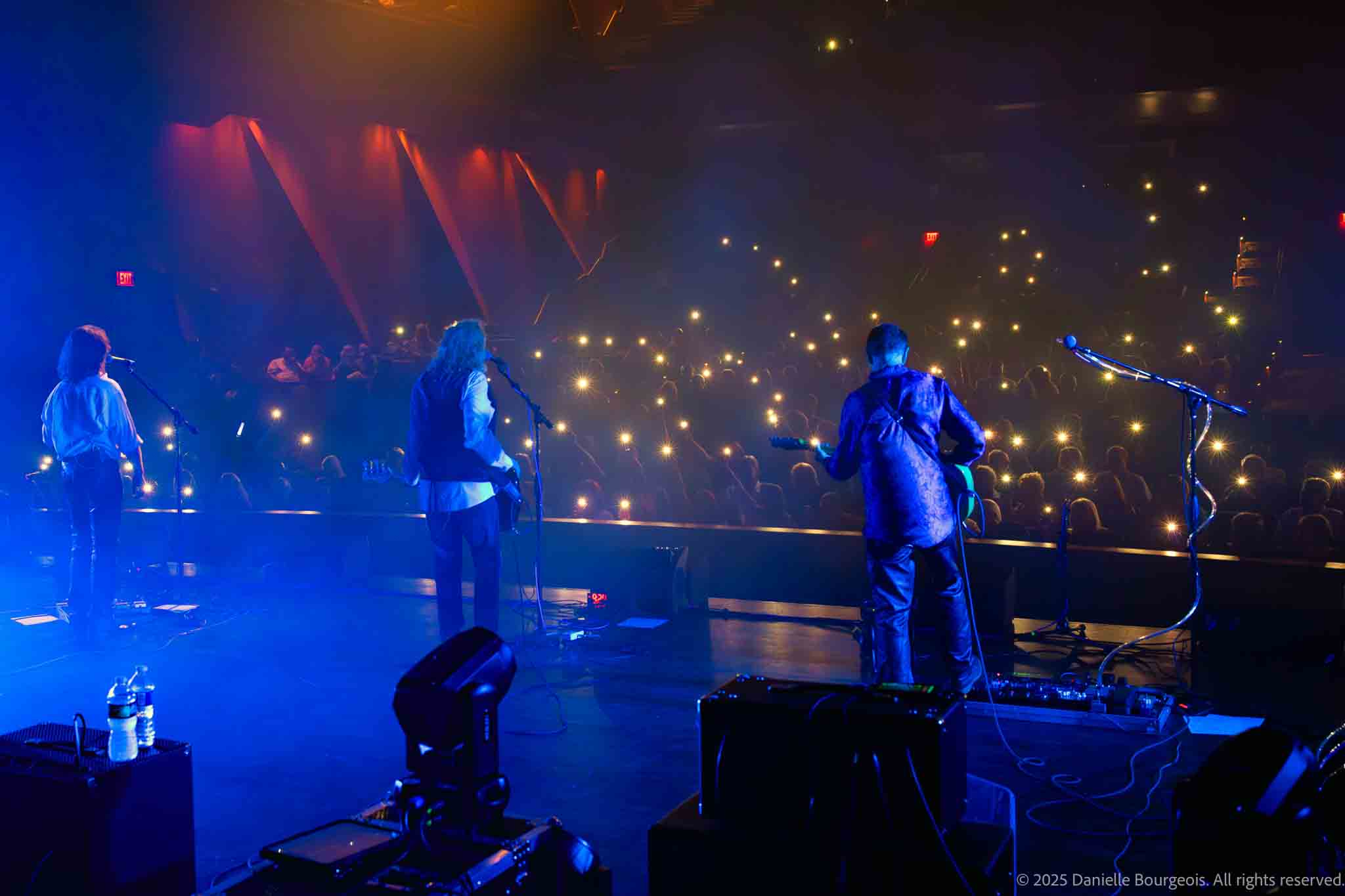 Clint Springer, Jay Bourgeois, and Harry Ochsenbein of Already Gone gaze out from the stage at a sea of glowing cell phones